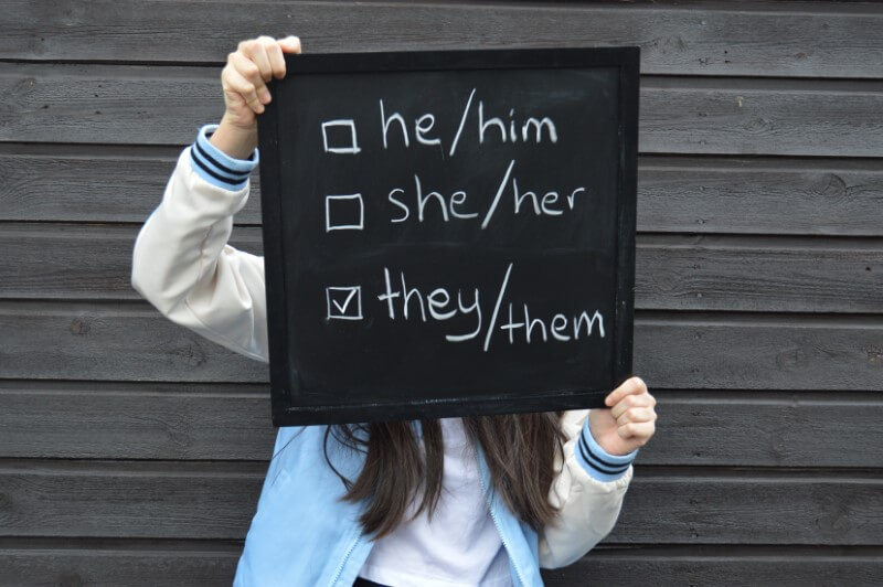 someone holding up board with pronoun options