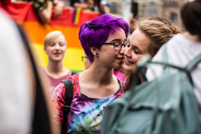 two young girls about to kiss at a pride march